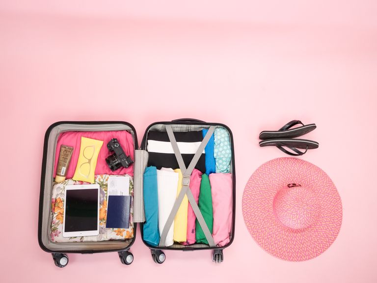 Open suitcase packed for a Caribbean vacation with sun hat and sandals